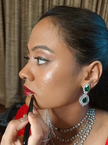 A close-up of me applying a bold red lip for this bride's sangeet. The look is traditional with a modern twist, featuring winged eyeliner and glowing skin.