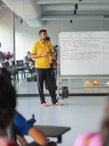 A trainer presents the key steps of CPR to an engaged audience of coaches and athletes, ensuring everyone understands the protocol.