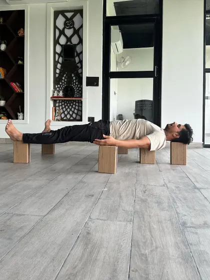 This is a supported Savasana on wooden blocks, inspired by Bhishma's bed of arrows in the Mahabharata. This pose, known as Sarapanjara, supports the cardiac nerve, bringing a state of restful alertness and opening the heart center.