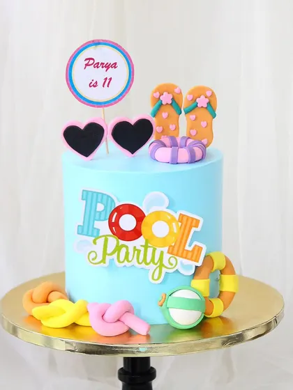 Time for a pool party! This fun, bright blue cake is perfect for a summer birthday, decorated with fondant flip-flops, sunglasses, and a pool float.
