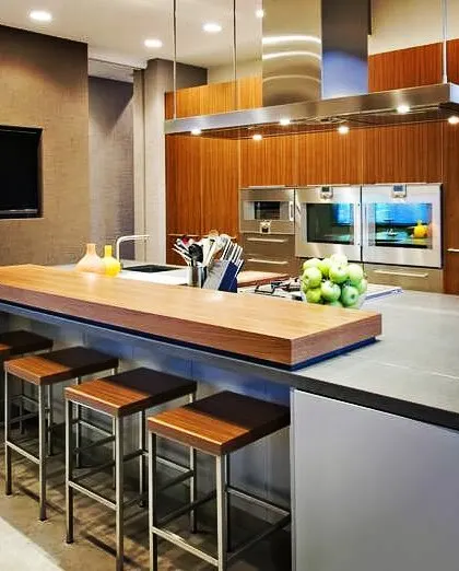 A kitchen is the heart of the home, and we design them to be both beautiful and functional. This modern open kitchen features a sleek island with a breakfast bar, integrated appliances, and warm wood finishes for a clean, contemporary look.