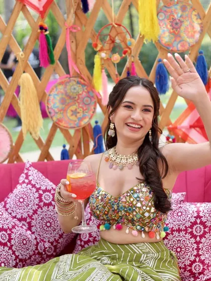 A candid shot of the bride waving, her colourful necklace adding to the fun vibe.