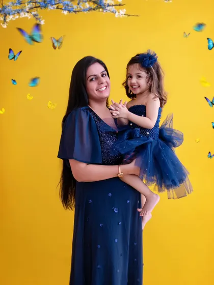 My studio offers a range of vibrant backdrops to match your family's personality. The bright yellow here contrasts beautifully with the matching blue outfits, creating a cheerful and eye-catching mother-daughter portrait.