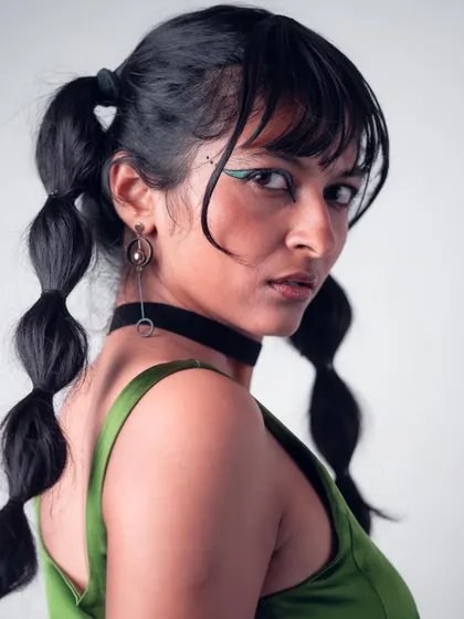 A close-up portrait with bubble pigtails and creative green eyeliner. This look from the 'Art in Motion' series highlights my features and edgy makeup styling.