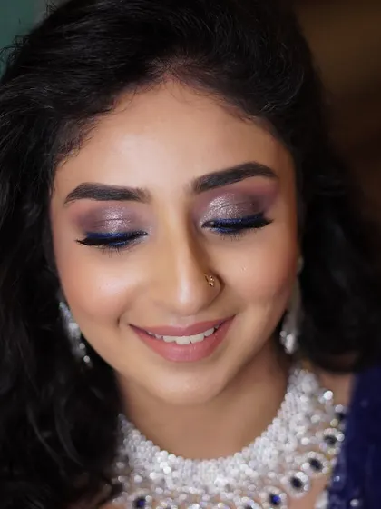 For a unique reception look, we added a pop of electric blue eyeliner over a shimmering, smokey base. It’s a modern and playful way to incorporate color into your bridal makeup.