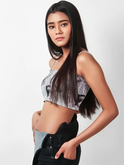 This mid-length shot captures a cool, casual look with a model in a printed crop top and black dungarees. The clean white background makes it ideal for a youth-focused fashion brand's catalogue.