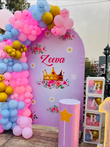 A princess-themed first birthday on a terrace. This setup features a custom purple backdrop, a multi-colored balloon arch, and 'BABY' blocks for a cute touch.