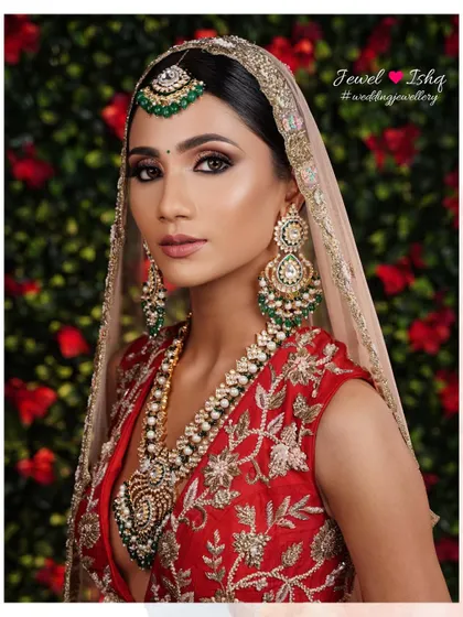A portrait of the bride in a red lehenga, her face framed by a beautiful dupatta. The statement earrings and layered necklace add a touch of grandeur.