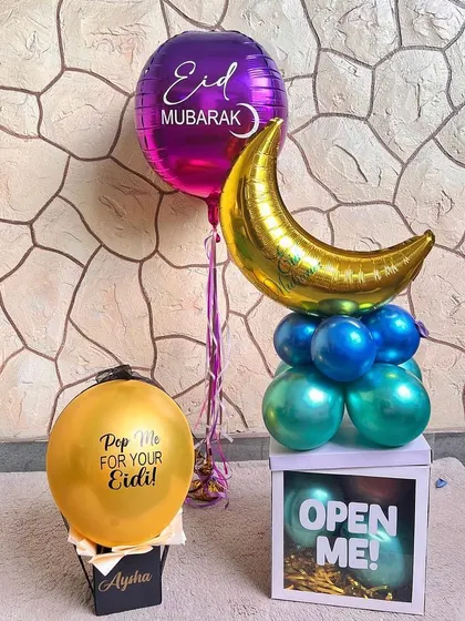 Gifting Eidi, our style. This collection includes a "Pop Me" balloon filled with a surprise, a stand with moon and star balloons, and an "Open Me" box for a fun and interactive gift experience.