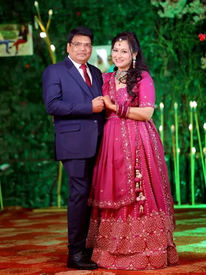 A classic portrait of the anniversary couple against a lush green backdrop with decorative lights, perfect for a milestone celebration.