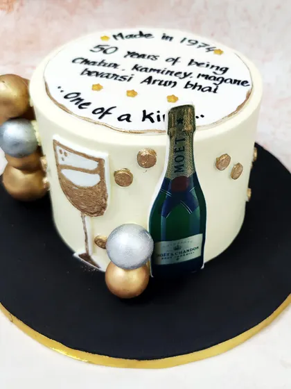 We raise a glass to a milestone birthday with this vintage champagne cake. Featuring a Moët bottle, a painted wine glass, and a personalized message, this cake is accented with gold and silver spheres for a celebratory and refined design.