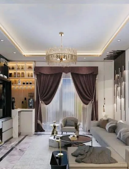 A sophisticated living room design featuring a sectional sofa, a stunning crystal chandelier, and a built-in bar and entertainment unit. The rich curtains and modern lighting create a luxurious atmosphere.