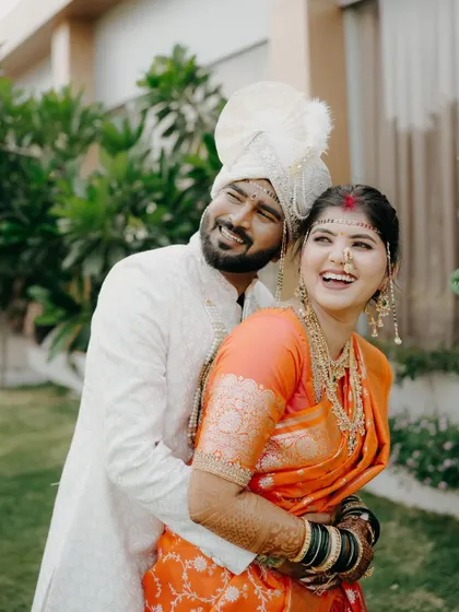 The groom embraces his bride from behind in this joyful, candid moment. Their genuine smiles are the centerpiece of this beautiful Maharashtrian wedding portrait.