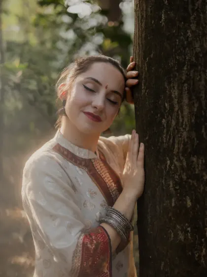 An intimate and serene portrait of the dancer. Leaning against a tree with her eyes closed, this shot captures a quiet moment of connection between the artist and nature.