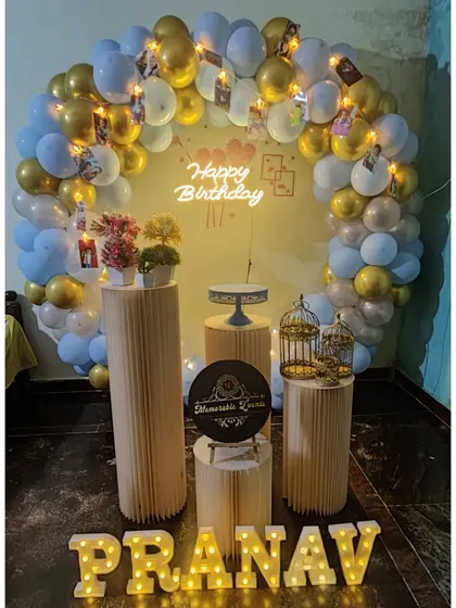 A birthday setup with a blue and gold balloon ring and personalized photo hangings.