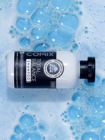 A top down shot of a shampoo bottle in a sea of blue foam. This textural and immersive photo effectively communicates the product's rich lather and deep cleansing action.