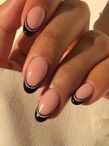 A chic and modern take on a classic, this design features a clean, double-lined black French tip on a perfectly shaped oval nail. It's an elegant and minimalist style that elevates any look with its sophisticated graphic detail.