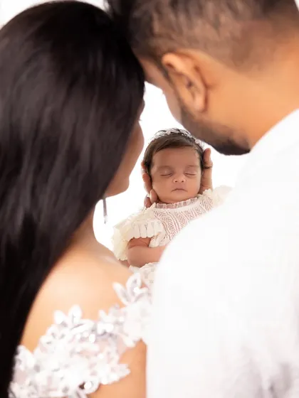 A creative and intimate shot of parents framing their newborn's face with their own. It symbolizes the baby being the center of their world.