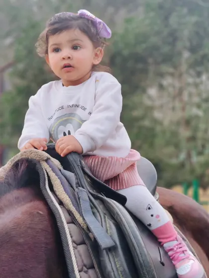 A sweet moment as a very young rider enjoys her gentle introduction to the world of horses.