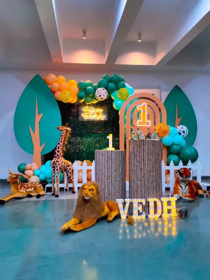Another angle of the wild jungle theme for Vedh's first birthday, showing the full scope of the animal props and the vibrant green and orange color scheme.