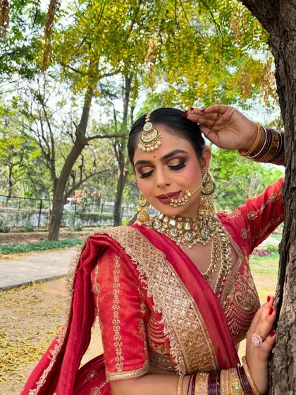 A close-up portrait of a bride, highlighting the detailed makeup and the heavy kundan jewellery that perfectly matches her red bridal attire.