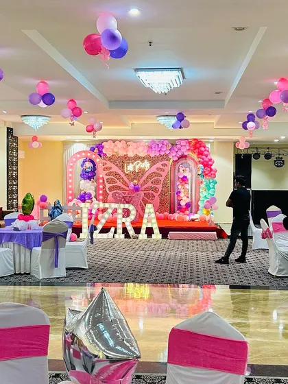 A full view of a banquet hall during a butterfly-themed party for "IZRA". This image shows the stage decor, table settings, and overall ambiance we create for large events.
