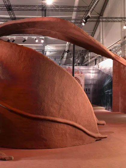 The large-scale leaf sculptures of the 'Terra' installation, viewed from below. This angle emphasizes their scale and the way they curve over the space, creating an architectural canopy that feels both natural and constructed.