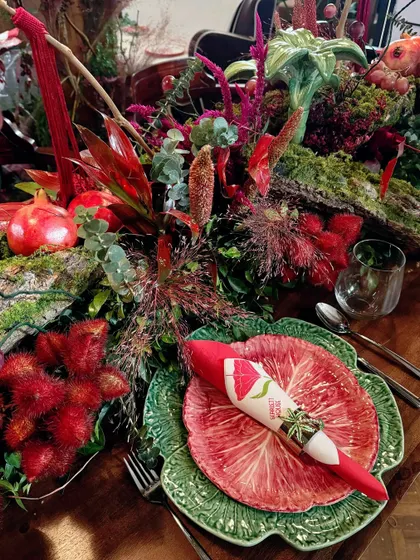 A place setting featuring a unique green leaf-patterned plate, contrasting beautifully with the rich red decor.