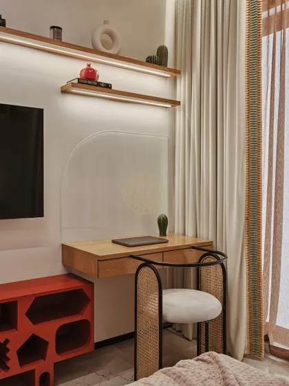 The kids' room includes a practical and stylish study area. A floating wooden desk is paired with a rattan chair, and an orange TV unit with drawers in different shapes adds more character and storage.
