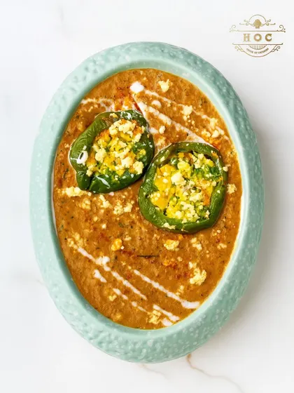 A creative take on a classic Indian dish. This preparation features bell peppers stuffed with spiced paneer, served in a rich, creamy gravy and presented in an elegant oval dish.