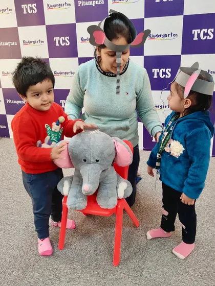 A teacher interacts with two little 'elephants'. Our concept-based learning activities are designed to be engaging and multi-sensory, ensuring the lesson sticks.