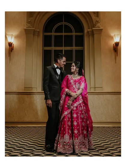 A full-length portrait of the couple against a checkered floor and grand window, looking elegant and happy.