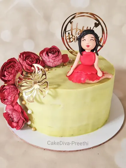 A pretty cake for a special girl, featuring a cascade of wafer paper flowers and a custom fondant figurine in a red dress.