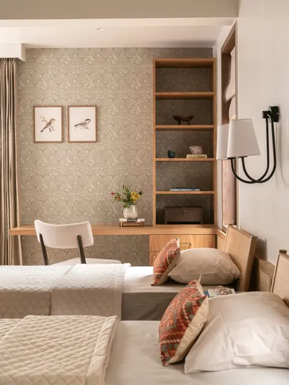 This guest bedroom features a built-in desk and shelving, making it a functional and comfortable space for visitors. The bird-themed wallpaper adds a touch of whimsy and charm.