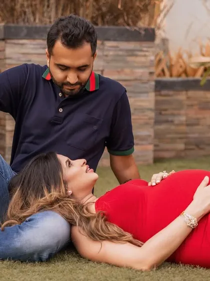 An outdoor maternity session offers a relaxed and natural feel. Here, the mother-to-be lies comfortably on the grass with her head in her partner's lap, sharing a look of love and happiness under the open sky.