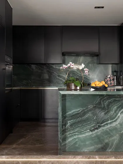 The custom kitchen island, crafted from a single piece of vibrant green marble. It's a bold, luxurious statement that anchors the entire open-plan living space.