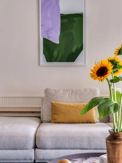 A close-up of the living area, showing how pops of color from the abstract art and fresh sunflowers energize the neutral sofa. This is how I layer details to create a space that feels both calm and full of life.