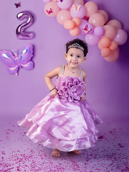 Twirling into her second year! This little girl in a beautiful purple dress celebrates turning two with a matching butterfly and balloon theme, full of joy and movement.