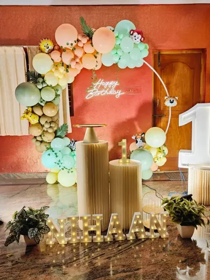 The full view of the pastel jungle theme for Nihaan's first birthday, including pedestals and marquee letters.