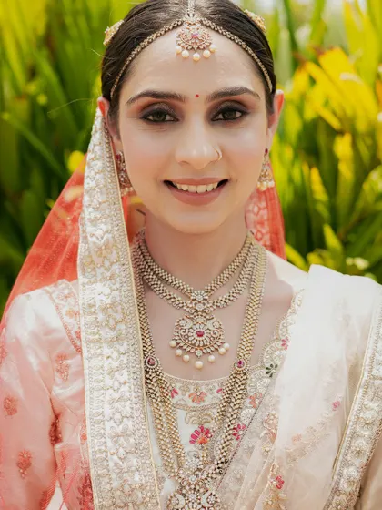 A bright and happy bridal portrait, her smile lighting up the frame, showcasing her stunning jewelry.