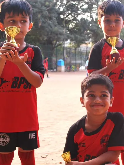 Three young champions from our toddler program with their well-earned trophies. Each trophy represents a milestone in their journey of learning and loving football.