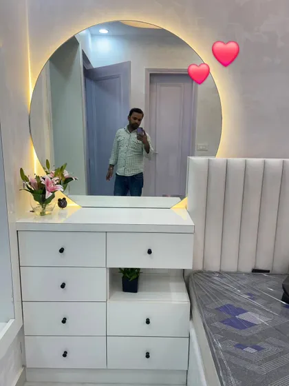 Creating an aesthetic and functional dressing area. This setup includes a large, round backlit mirror and a floating vanity with multiple drawers for storage.