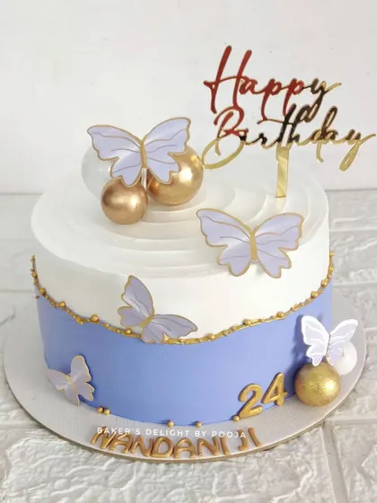A simple and elegant butterfly cake. The design features a two-tone effect with purple and white, adorned with delicate butterflies and golden spheres for a touch of magic.