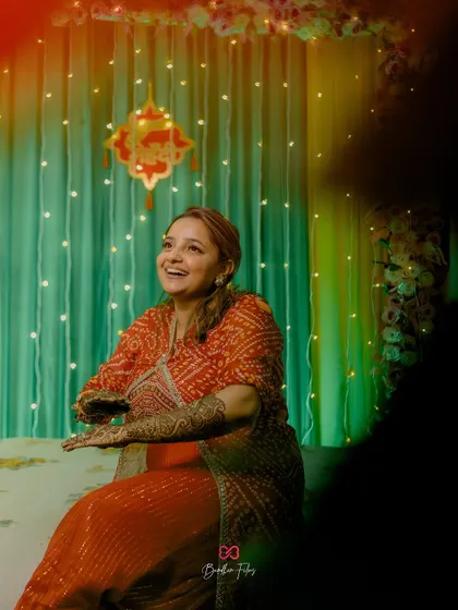 A candid shot of the bride laughing during her Mehendi ceremony, with fairy lights creating a warm and magical atmosphere.