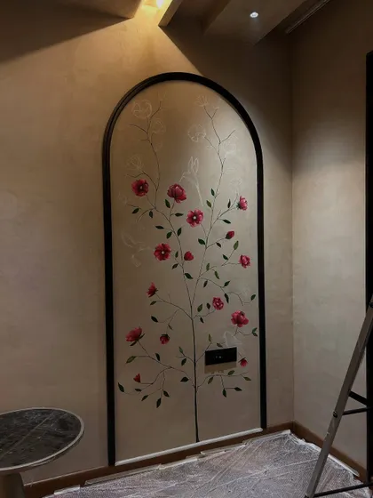 The floral mural nearing completion. The climbing vine with pink blossoms is designed to look as if it's growing naturally within the arched frame.