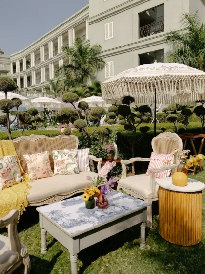 A charming lounge area at the Mehendi, with vintage-style furniture and custom-printed cushions, set against the manicured gardens of the palace.