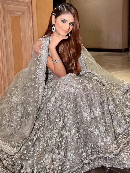 For a glamorous reception or cocktail party, I offer outfits like this stunning silver-grey gown. The entire piece is covered in intricate sequin and crystal work and includes a matching cape for a truly show-stopping entrance.