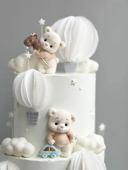A close-up of the adorable, handcrafted teddy bear toppers on the white celebration cake.