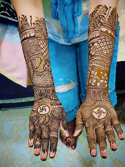A traditional design incorporating Swastika symbols on the palms for good fortune. The forearms are covered in dense, symmetrical patterns.