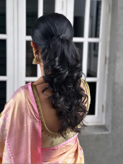 A modern half-up, half-down hairstyle with voluminous curls for Keerthi. This style is perfect for receptions and sangeets, offering a look that is both elegant and playful.